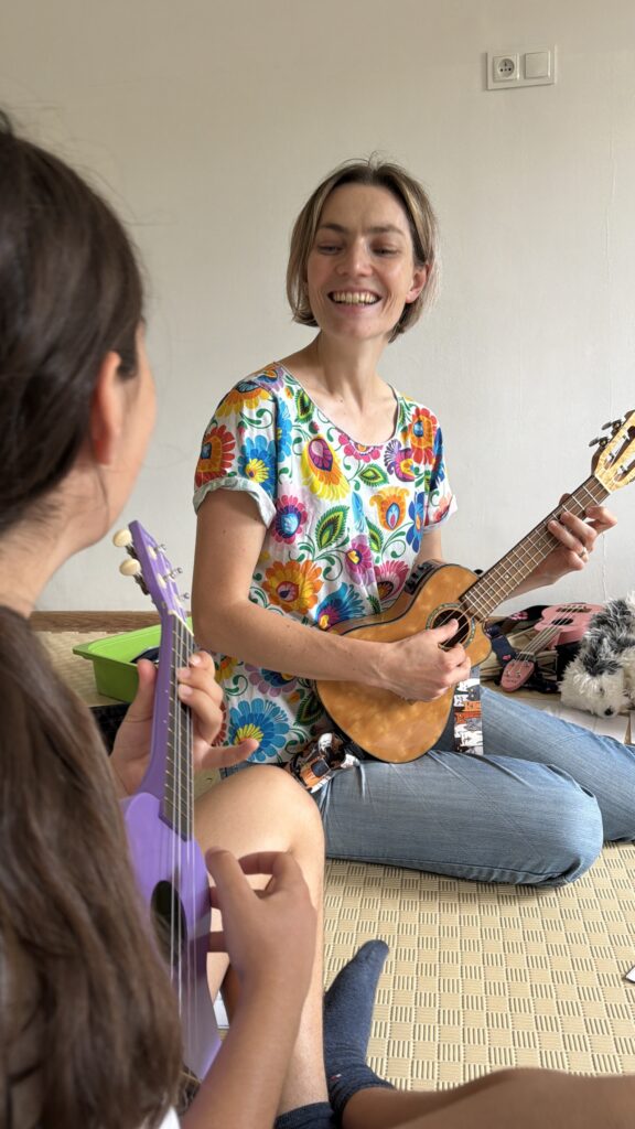 Dziewczynka grająca na ukulele podczas zajęć muzycznych.